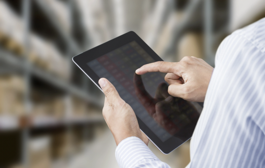 person clicking on a tablet in a warehouse