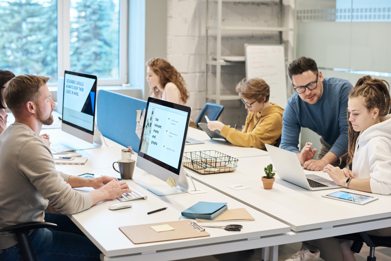 people with computer screens on a table in front of them, a help desk